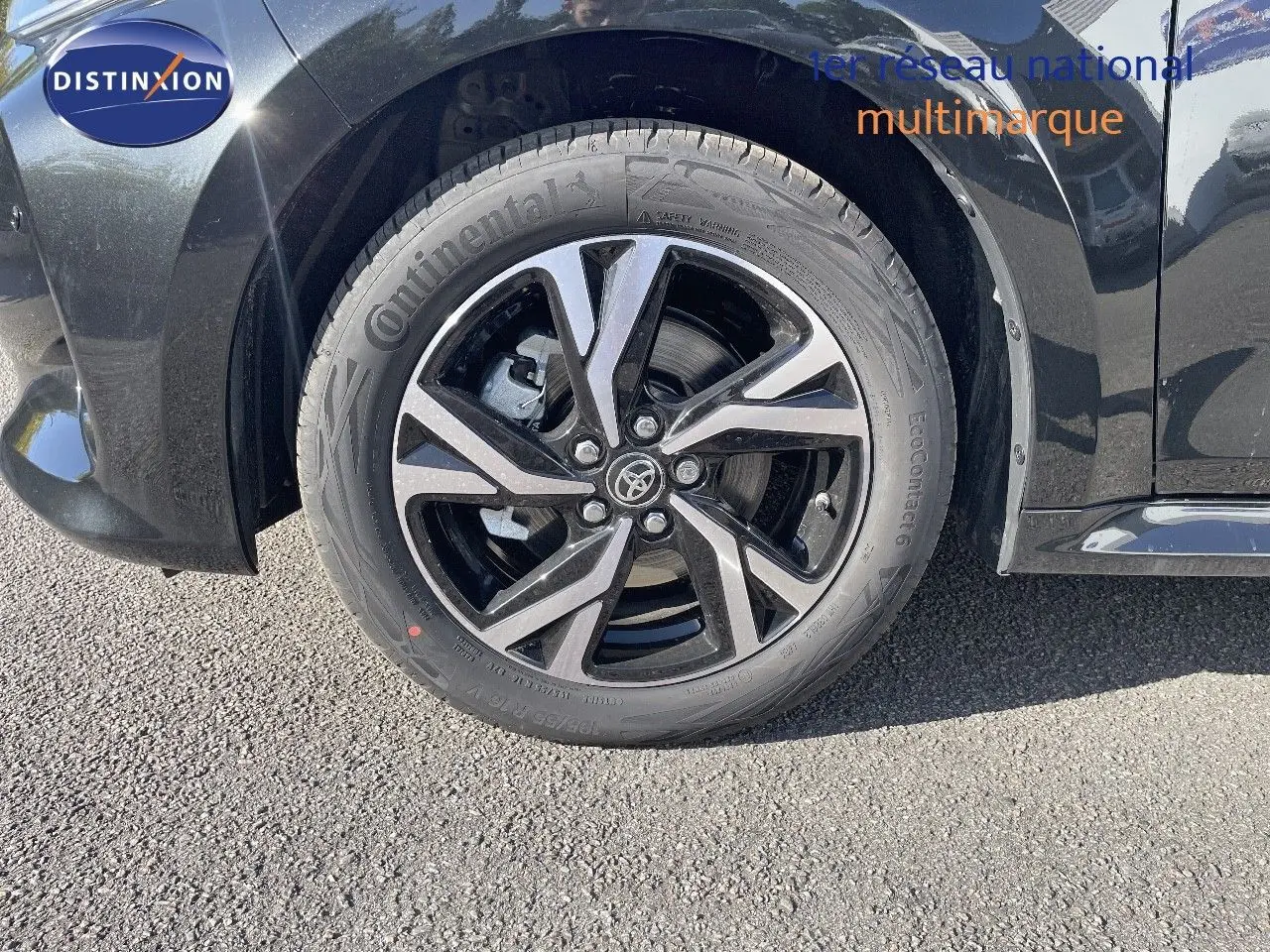 Gros plan sur la roue avant gauche noire métal de la Toyota Yaris Hybrid 116ch Design 2025 avec jante alliage bicolore.