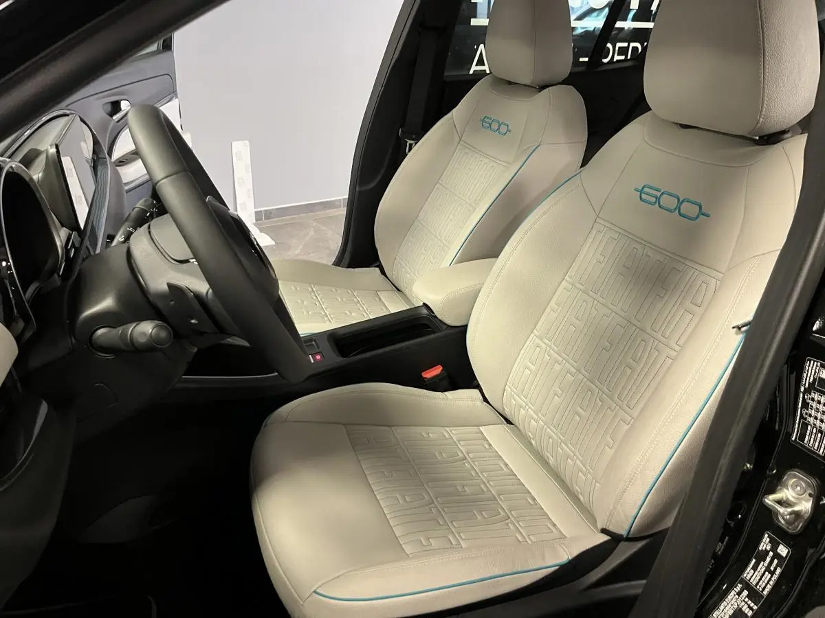Intérieur vue côté gauche du FIAT 600 noir, sièges ivoire embossés avec logo 600 bleu azur et volant soft-touch.