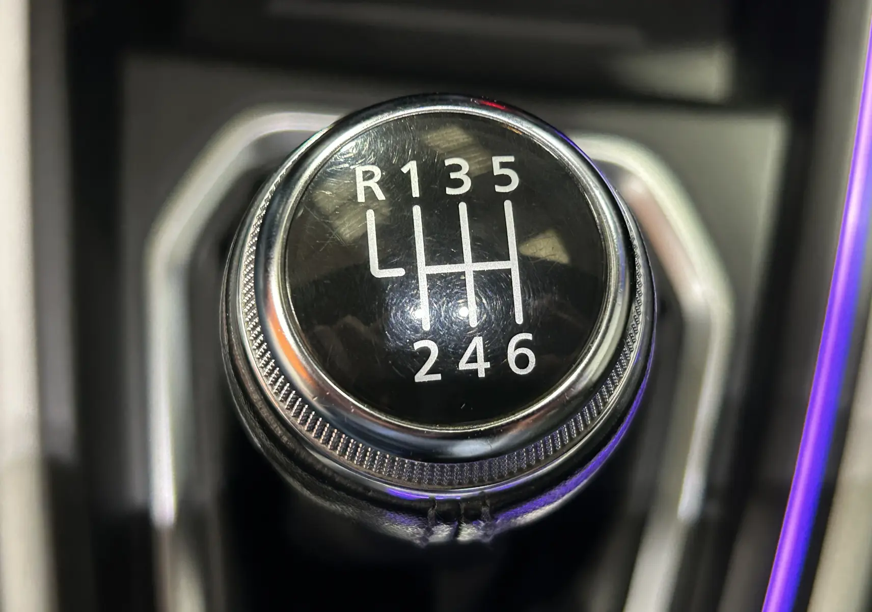 Gros plan sur le levier de vitesses manuel noir et chrome de la Renault Clio V TCe 90 TECHNO rouge, montrant les six rapports et la marche arrière.