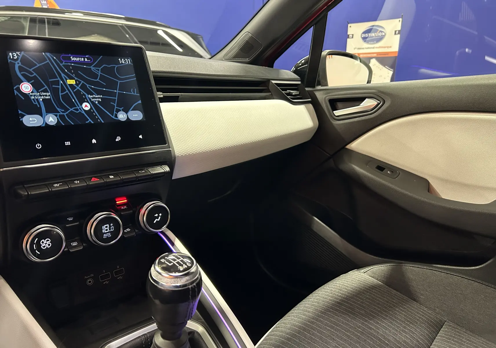 Intérieur de Renault Clio V TCe 90 TECHNO 2023, vue côté passager montrant la console centrale avec boîte manuelle et écran tactile.