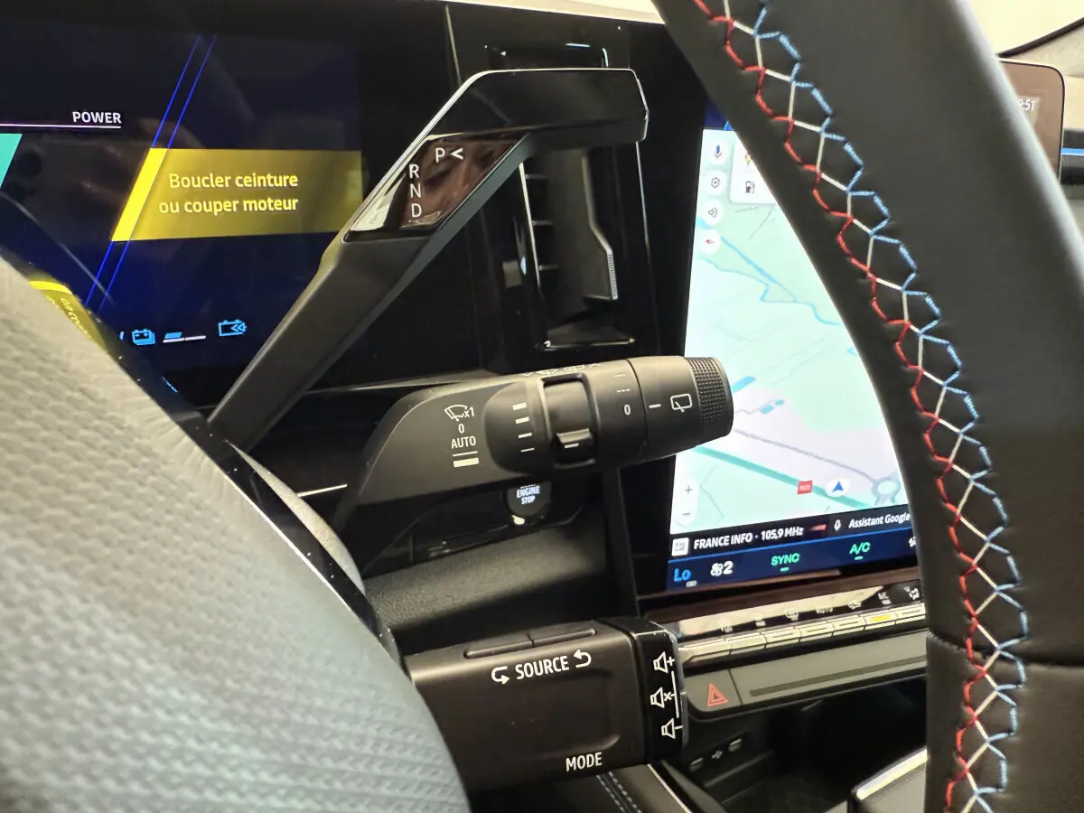 Gros plan sur la console centrale et volant cuir noir avec surpiqûres tricolores du Renault Espace gris foncé 2025 esprit Alpine.