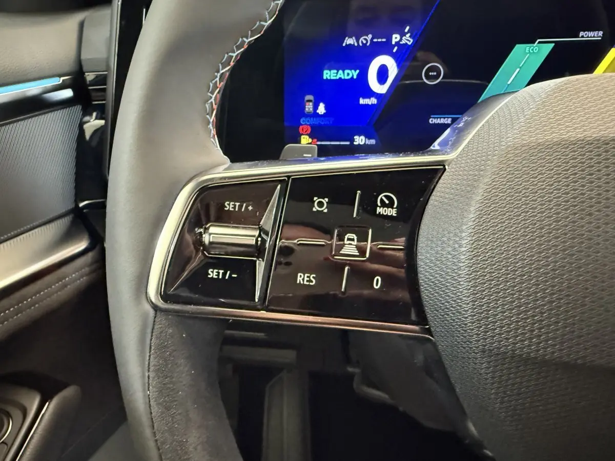 Gros plan sur les commandes du volant côté gauche du Renault Espace esprit Alpine gris foncé avec affichage numérique bleu en arrière-plan.