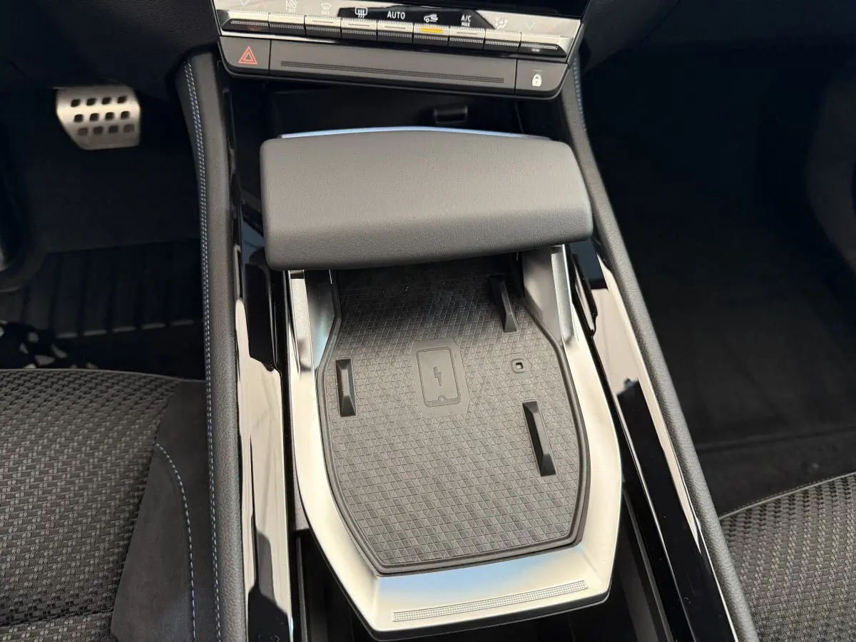 Vue rapprochée de la console centrale du Renault Espace esprit Alpine 2025 avec zone de recharge sans fil et accoudoir gris foncé.