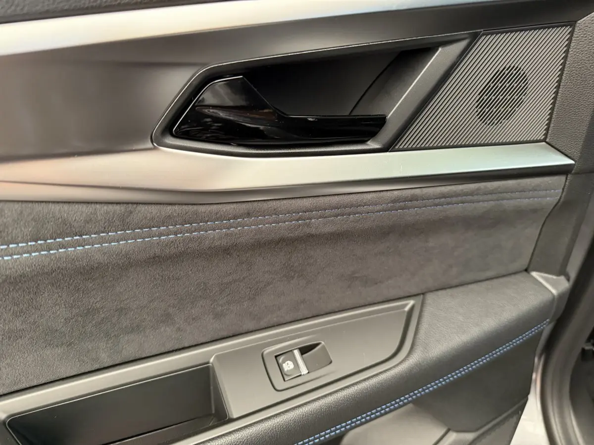 Détail de la porte côté conducteur du Renault Espace gris foncé 2025, avec surpiqûres bleues et poignée noire brillante.