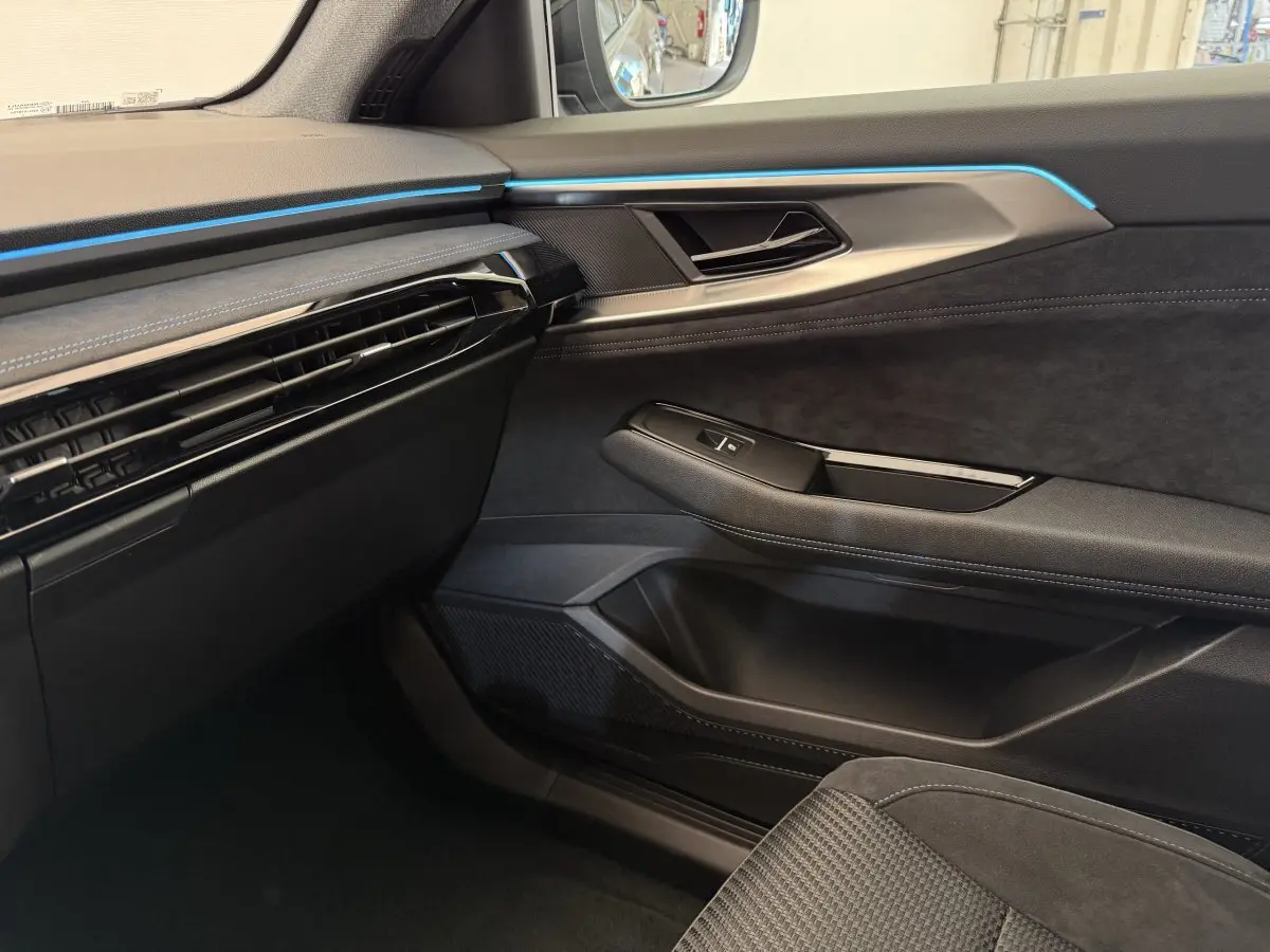 Intérieur côté passager du Renault Espace 2025 esprit Alpine, ambiance sombre avec bandeau lumineux bleu subtil.