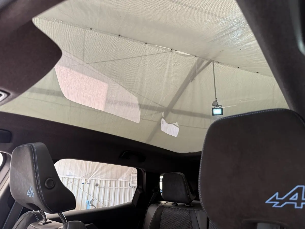 Vue intérieure du toit panoramique et des sièges avant noirs avec logo Alpine bleu sur un Renault Espace gris foncé.