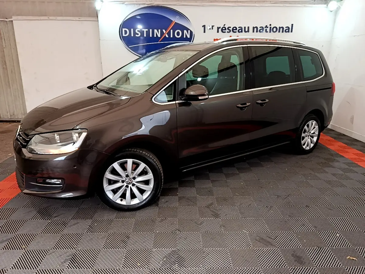 Volkswagen Sharan marron vue de profil côté gauche dans un showroom avec sol à damier et logo Distinxion en arrière-plan