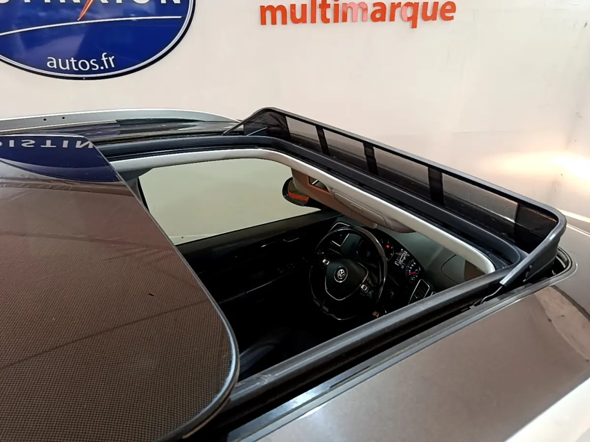 Vue plongeante sur le toit ouvrant panoramique d'un Volkswagen Sharan marron, montrant l'intérieur et le volant cuir.