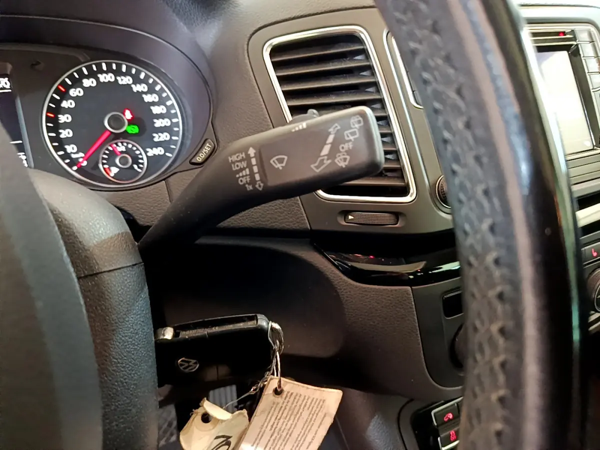 Gros plan sur le volant et le commodo d’essuie-glace du Volkswagen Sharan 2017, intérieur noir avec tableau de bord visible.