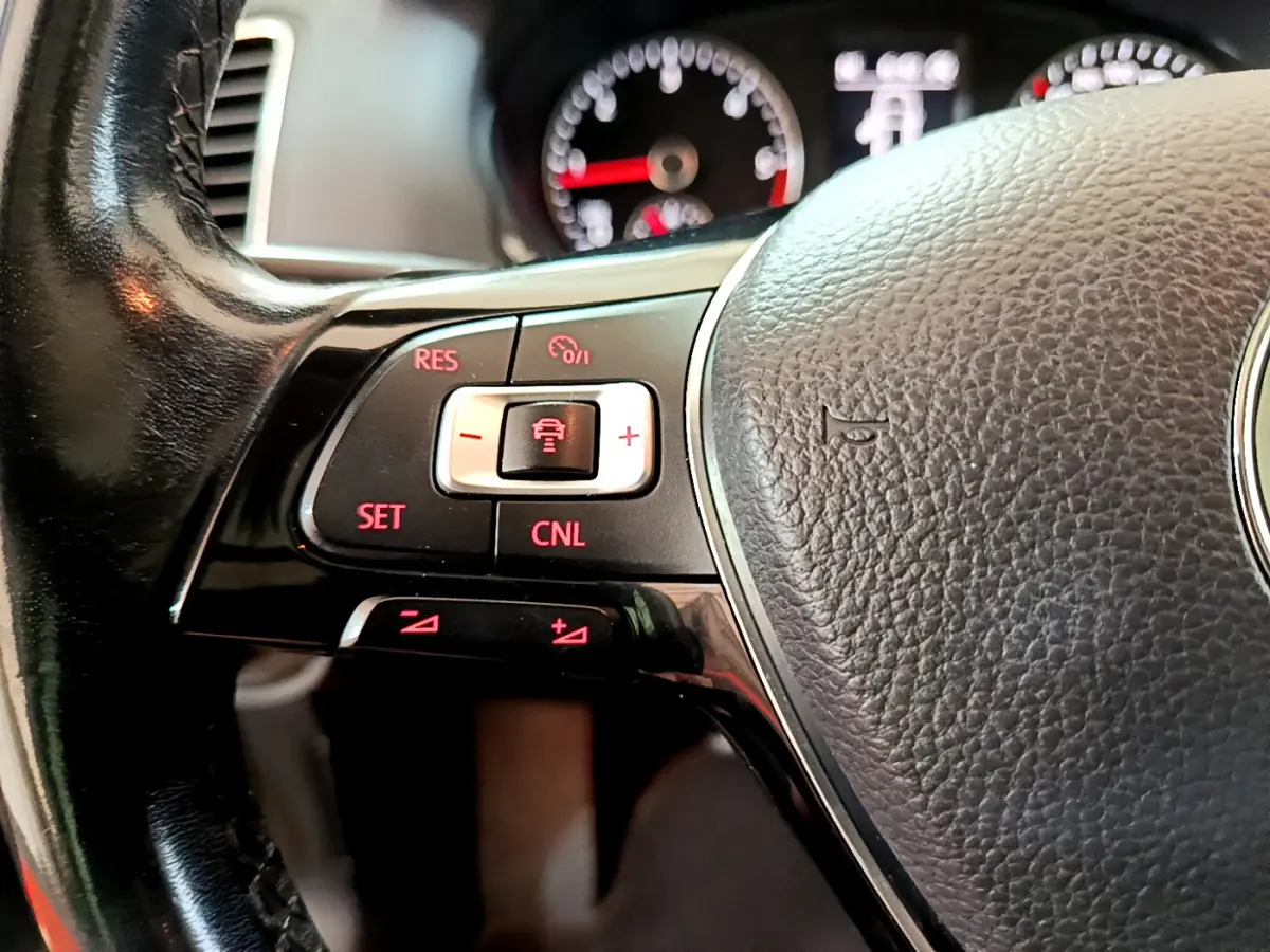 Gros plan sur le volant cuir noir de la Volkswagen Sharan 2017, avec commandes de régulateur adaptatif éclairées en rouge.