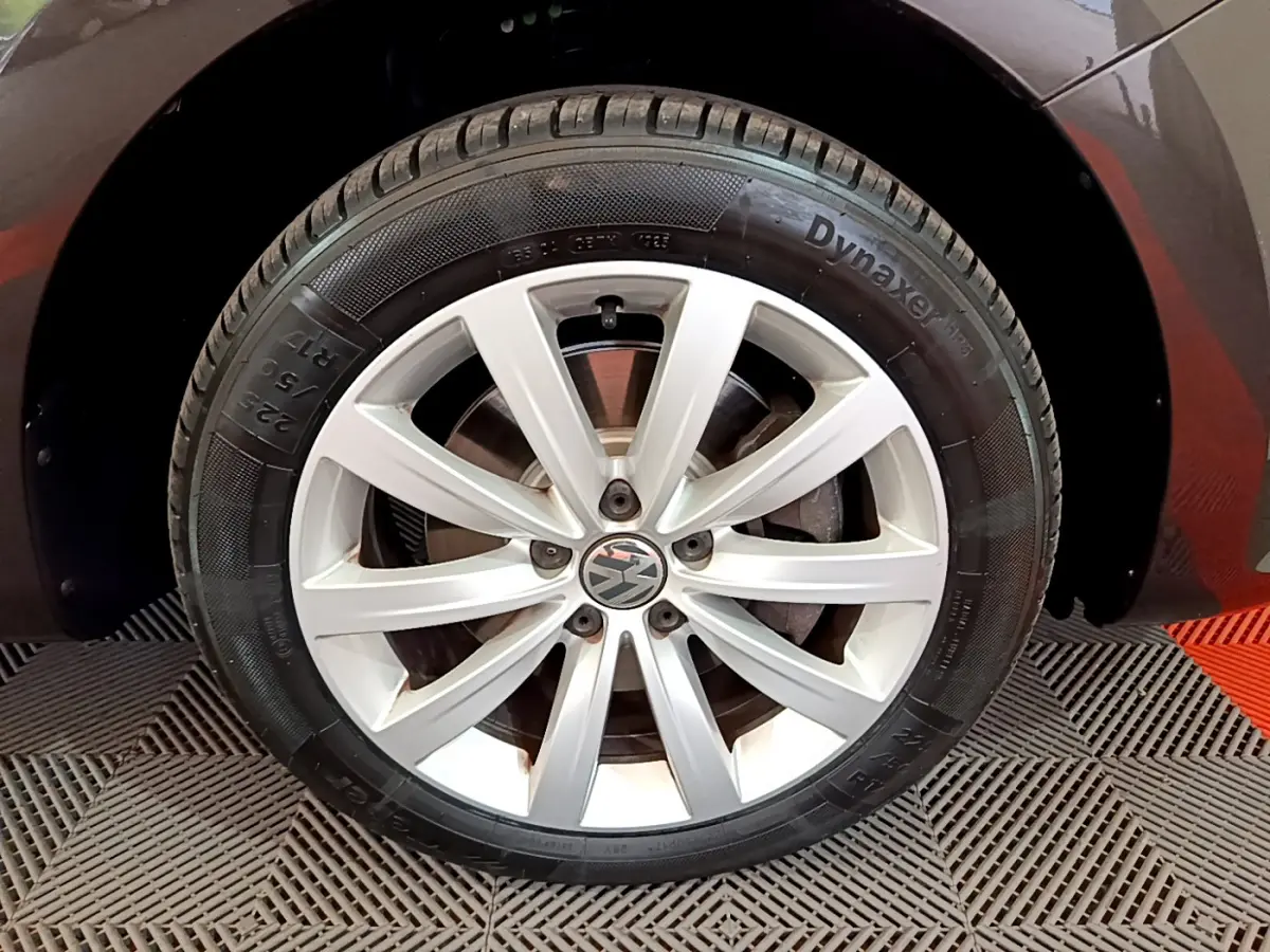 Gros plan sur la roue avant droite avec jante argentée du Volkswagen Sharan marron 2017.