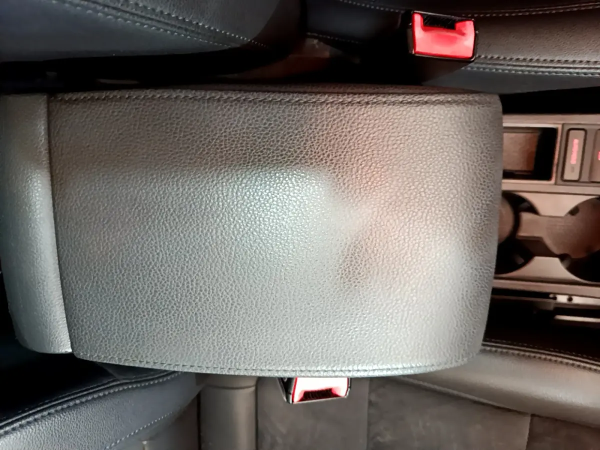 Gros plan sur l'accoudoir central en cuir noir et la console avec porte-gobelets du Volkswagen Sharan marron 2017.