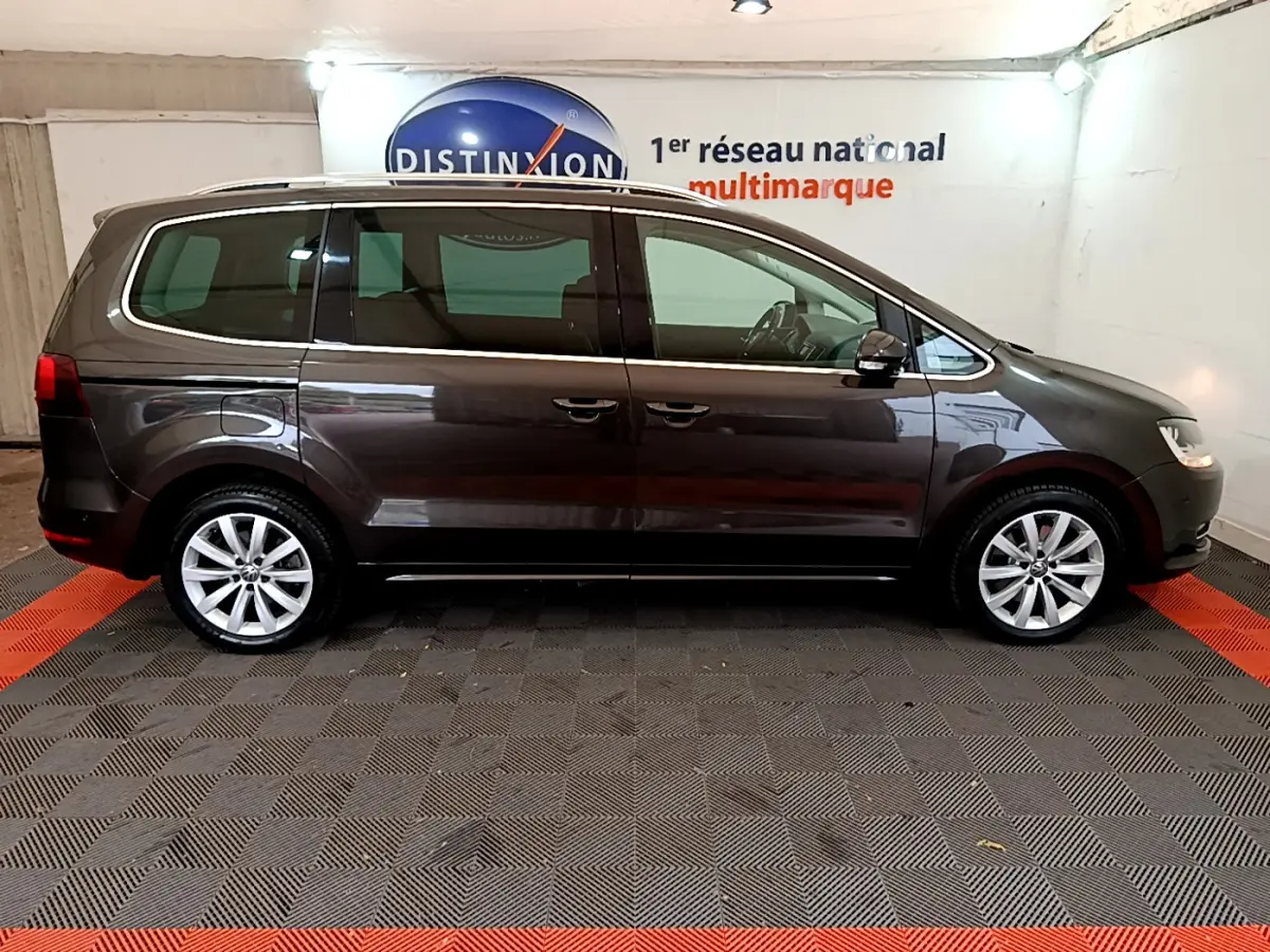 Profil latéral droit d'un Volkswagen Sharan marron 2017 dans un showroom avec sol en damier noir et rouge.