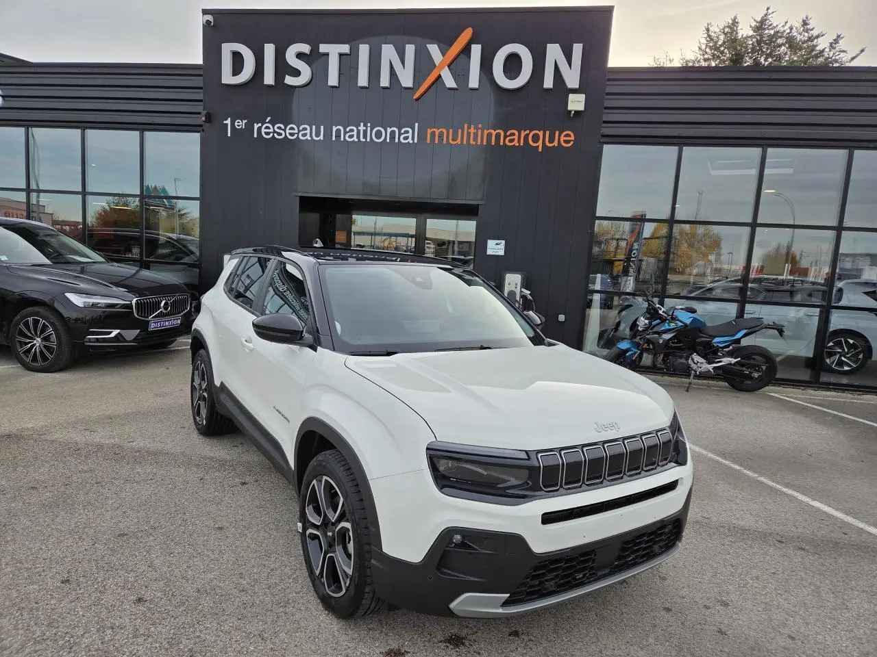 Jeep Avenger blanc Snow avec toit noir Volcano, vue 3/4 avant, calandre gloss black et jantes alliage 18 pouces.