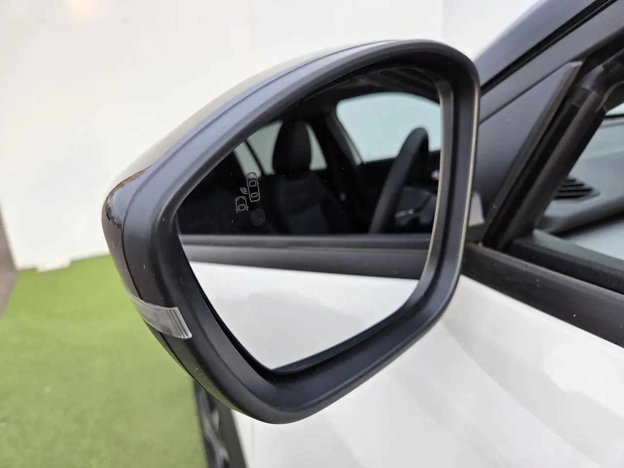 Rétroviseur extérieur côté gauche noir brillant sur Jeep Avenger Snow avec intérieur visible en arrière-plan.