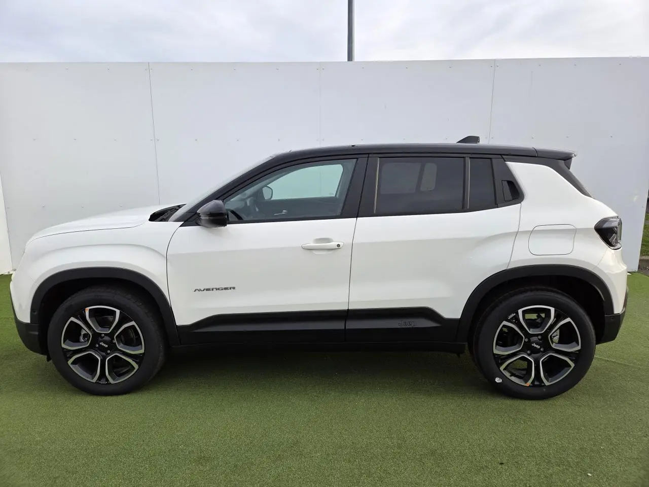 Profil côté gauche du Jeep Avenger 2025 blanc Snow avec toit noir Volcano et jantes alliage 18 pouces.