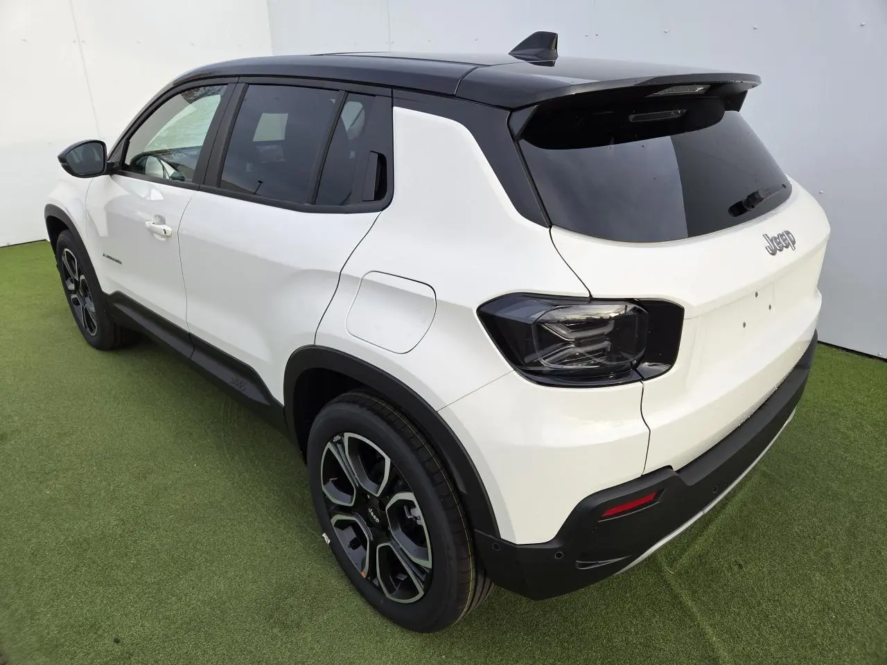 Jeep Avenger hybride 2025 vue 3/4 arrière côté gauche, carrosserie blanche Snow et toit noir Volcano.