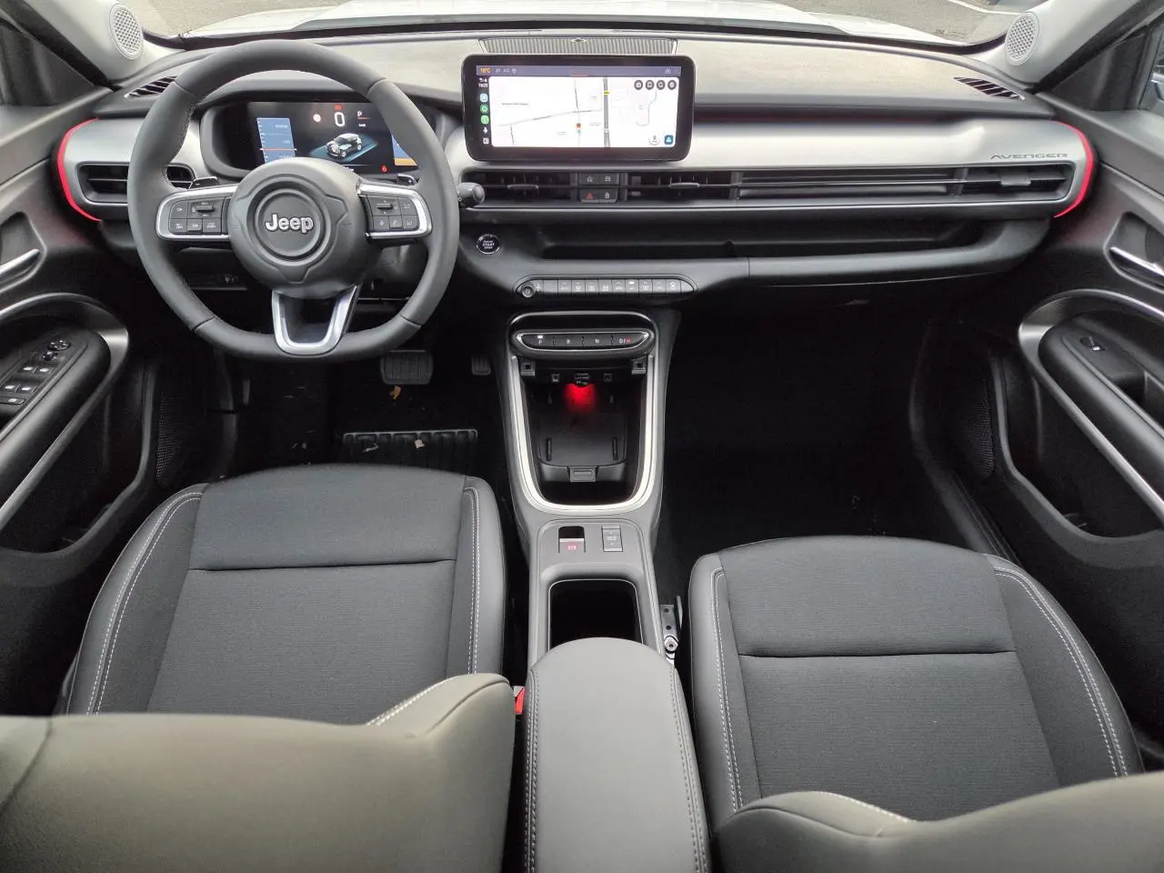 Vue intérieure frontale du Jeep Avenger 2025 avec tableau de bord noir, écran tactile central et volant multifonction.