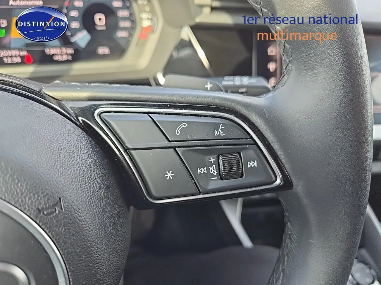 Gros plan sur les commandes au volant cuir noir de l’Audi A3 Sportback gris Daytona, avec palettes au volant visibles.