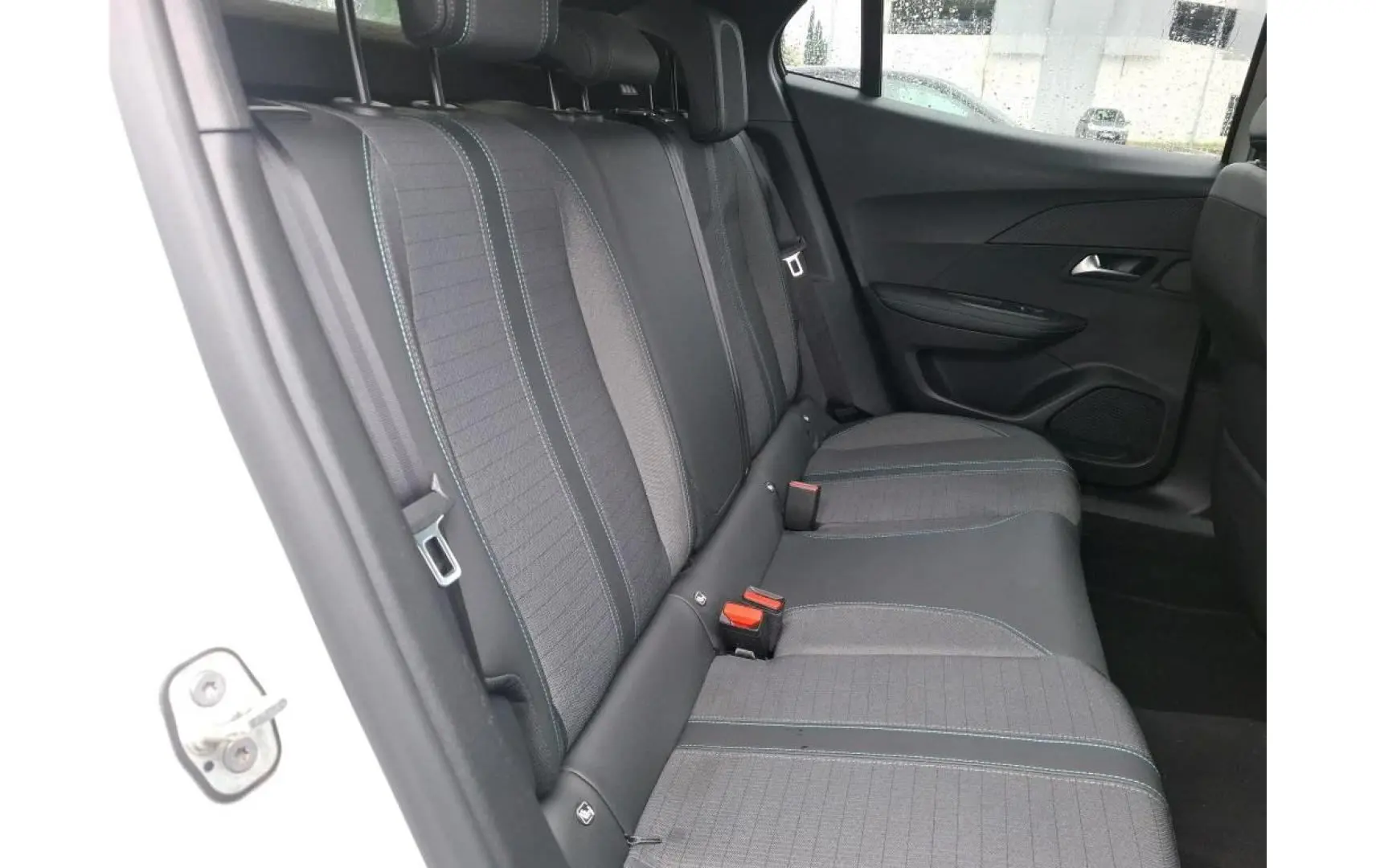 Vue intérieure côté arrière droit montrant les sièges arrière gris avec surpiqûres bleues du Peugeot 2008 blanc nacré 2022.