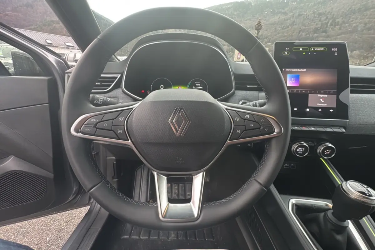 Vue intérieure centrée sur le volant cuir multifonctions et l’écran tactile 9,3 pouces de la Renault Clio gris schiste.