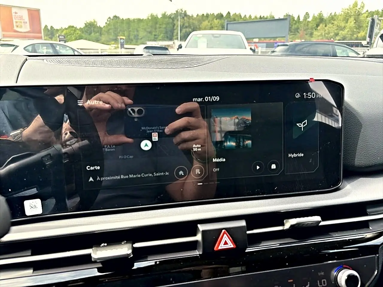Écran tactile central du Kia Sportage 1.6 hybride 239, affichant navigation et mode hybride, intérieur noir.