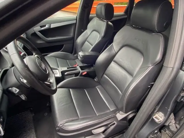 Intérieur noir de l'Audi RS3 Sportback 2012 vu côté conducteur, mettant en valeur les sièges cuir et le volant multifonction.