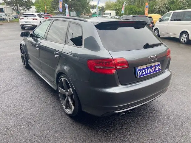 Audi RS3 Sportback gris Daytona vue 3/4 arrière droit, avec jantes sport et vitres teintées.