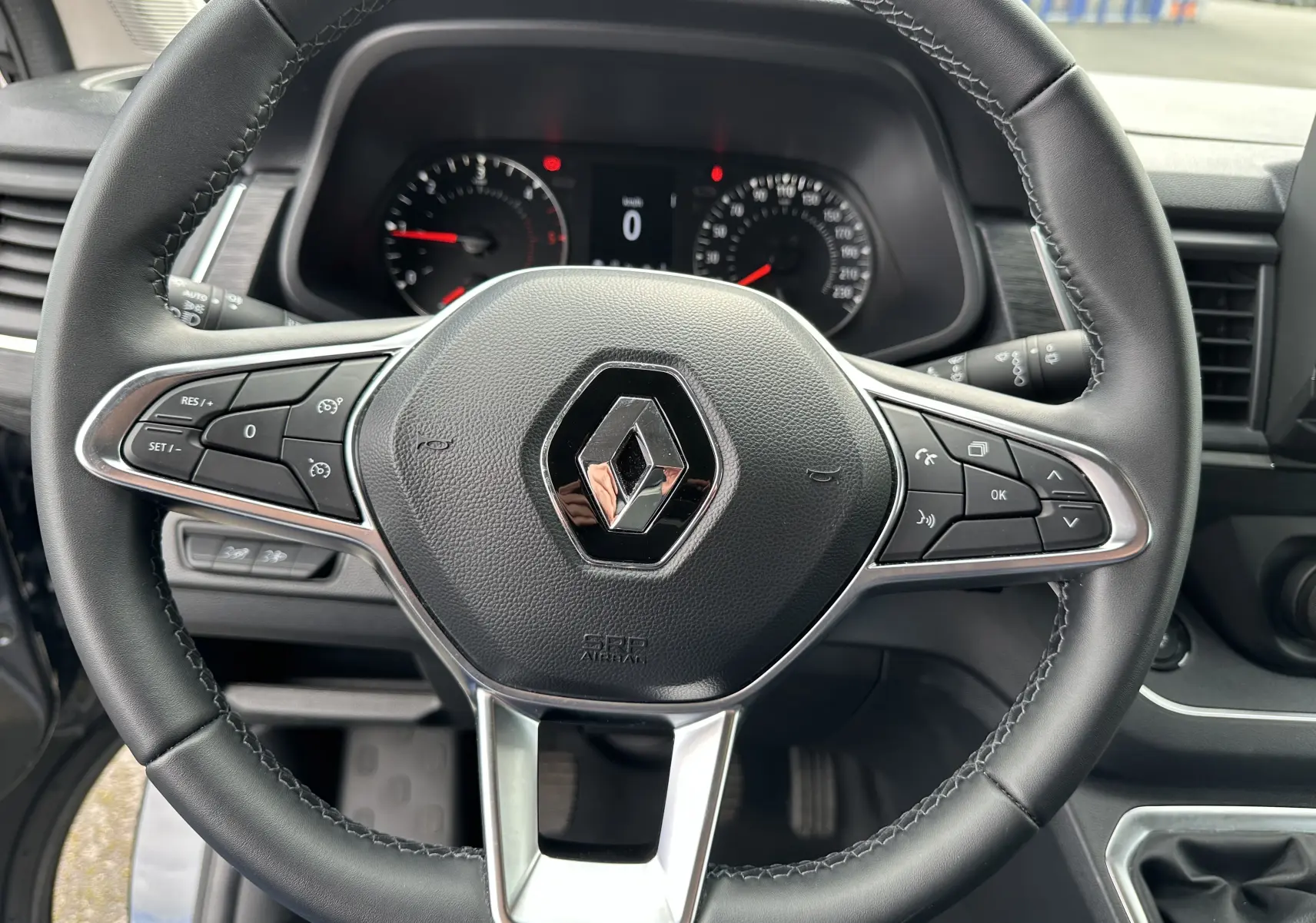 Gros plan sur le volant noir du Renault Trafic Combi 2023 avec commandes intégrées et tableau de bord visible.