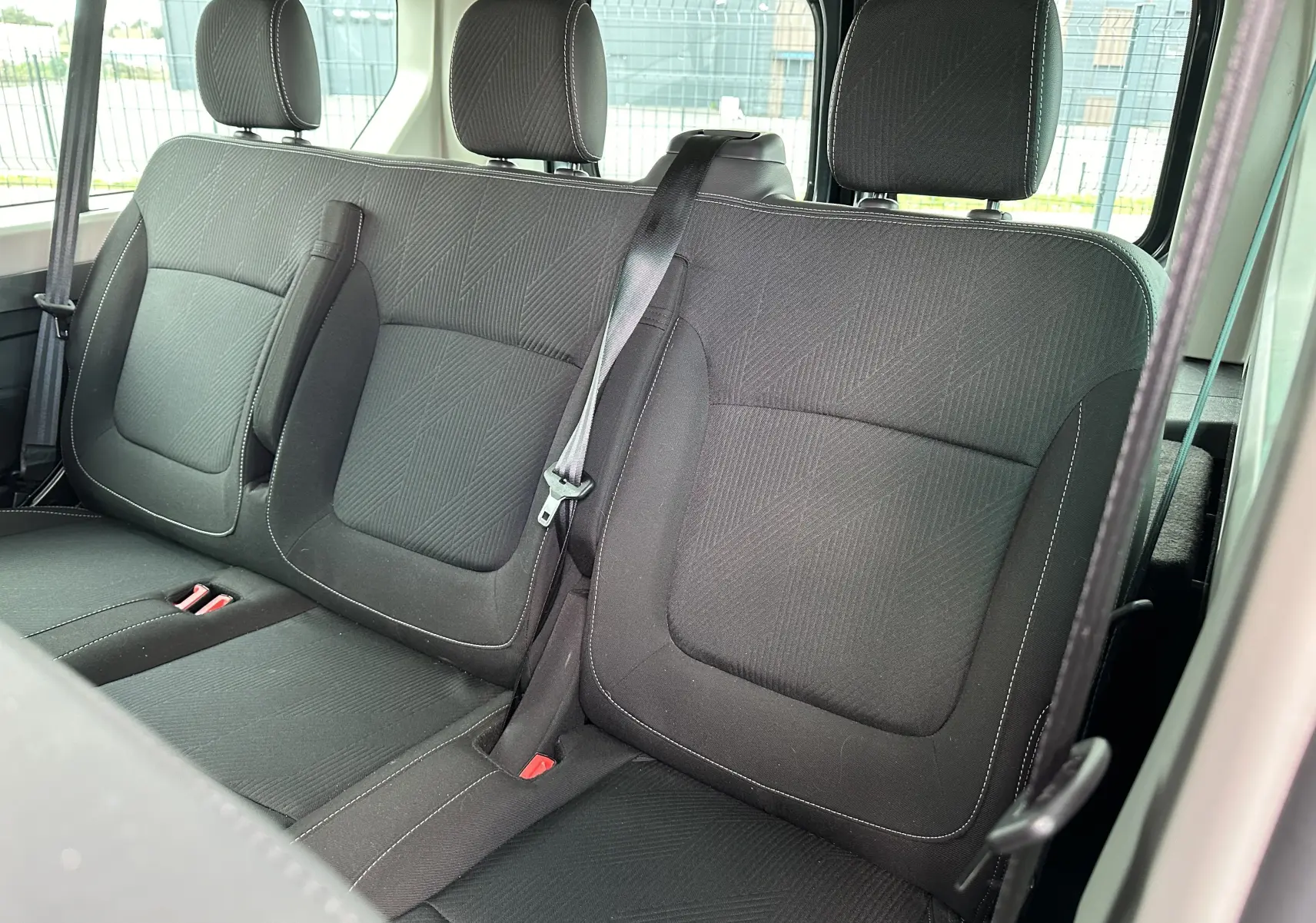 Vue rapprochée des sièges arrière noirs en tissu du Renault Trafic Combi 2023, version 9 places, avec ceinture de sécurité visible.