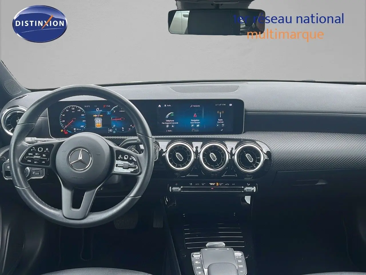 Tableau de bord et volant noir d'une Mercedes Classe CLA Shooting Brake 180 Diesel, avec écran digital large et aérateurs ronds.