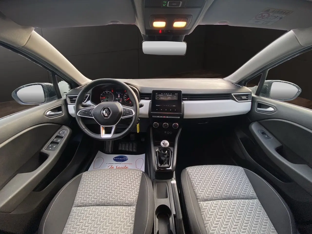 Vue intérieure avant de la Renault Clio V TCE 90 Evolution, sellerie beige et tableau de bord avec écran tactile central.