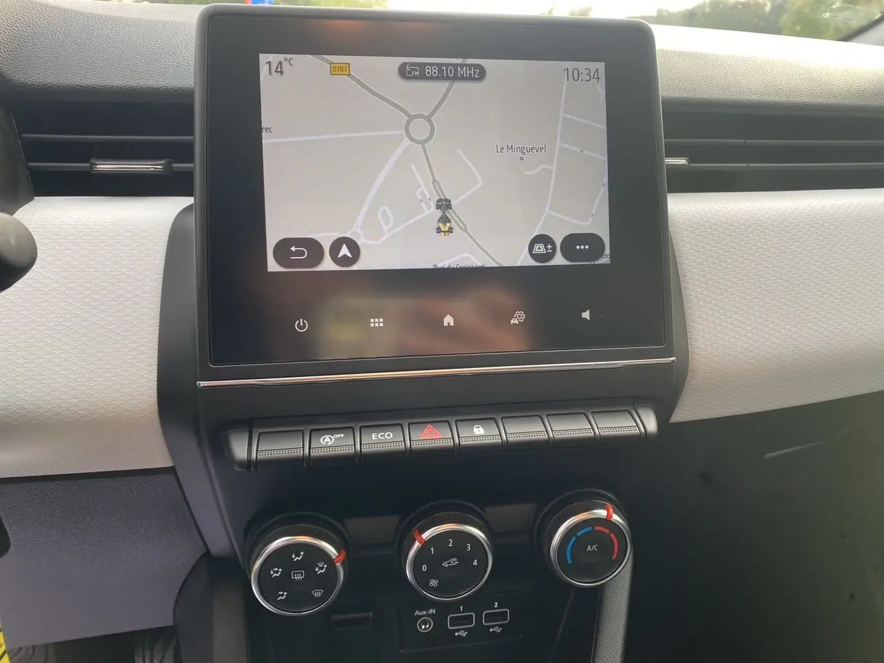 Vue rapprochée du tableau de bord beige et noir de la Renault Clio V avec écran tactile 7 pouces et commandes de climatisation.