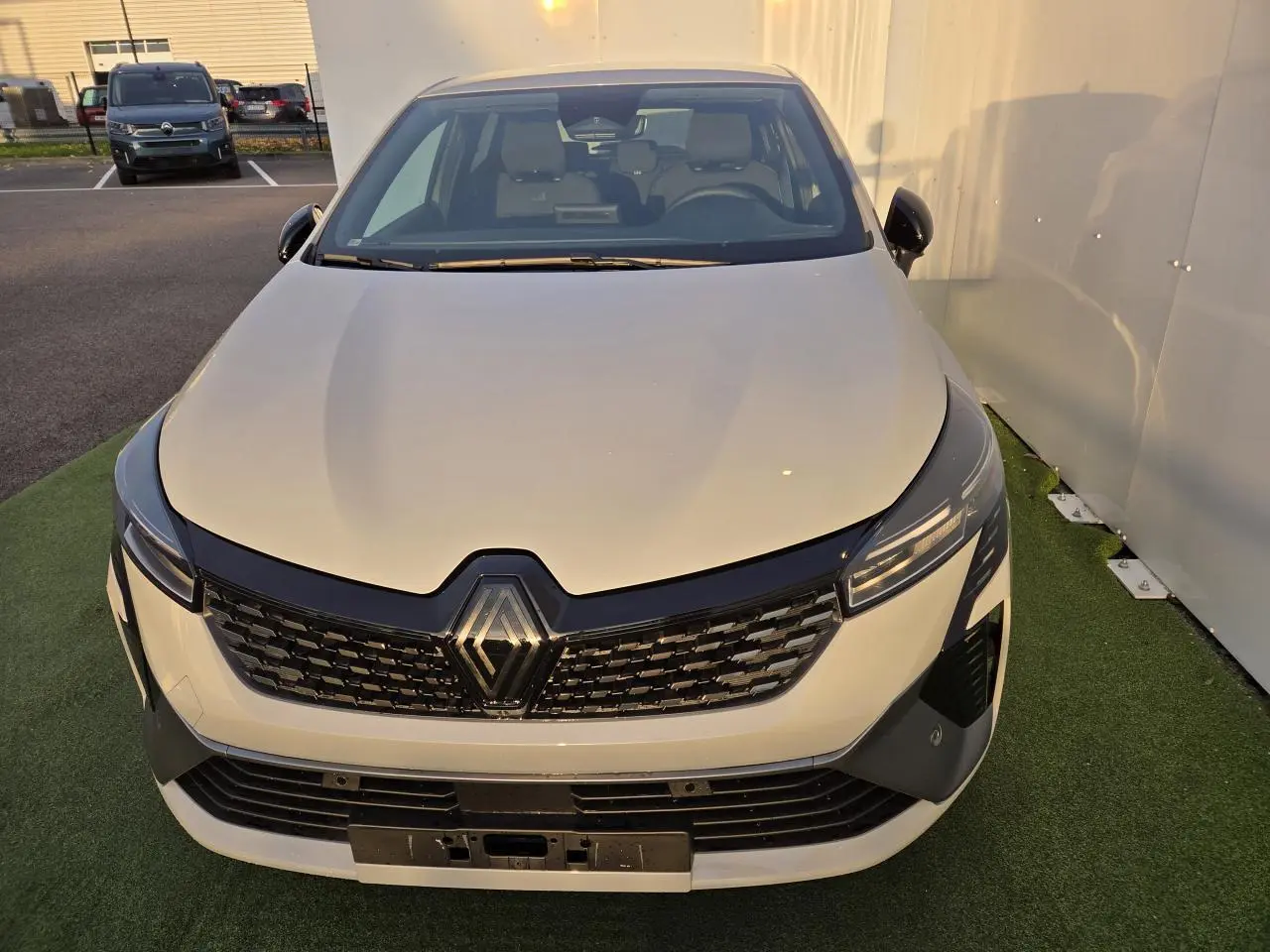 Vue avant rapprochée d'une Renault Clio V hybride gris Rafale avec calandre noire et phares LED fins.