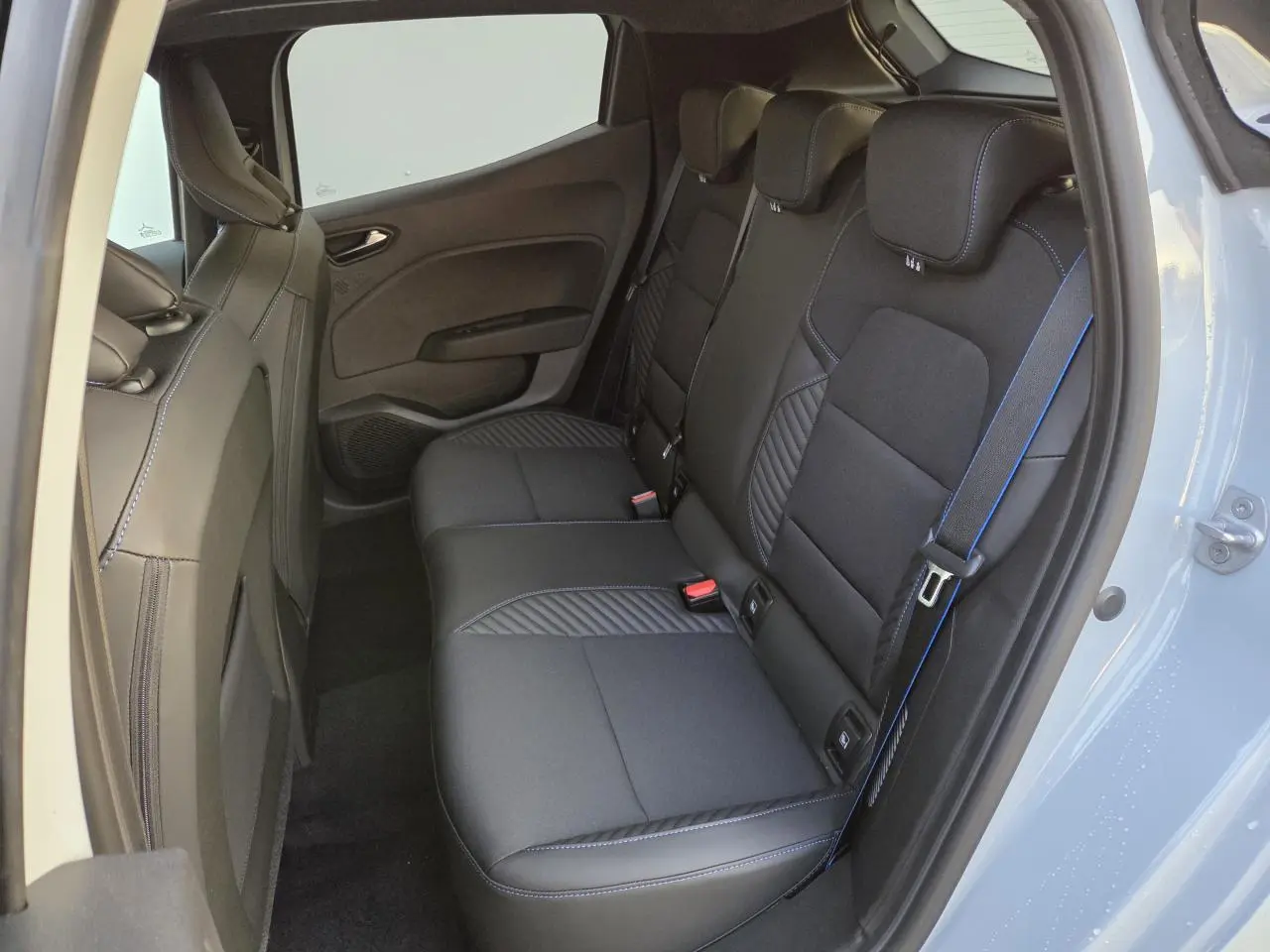 Vue côté droit de la banquette arrière noire avec surpiqûres bleues de la Renault Clio V Gris Rafale 2025.