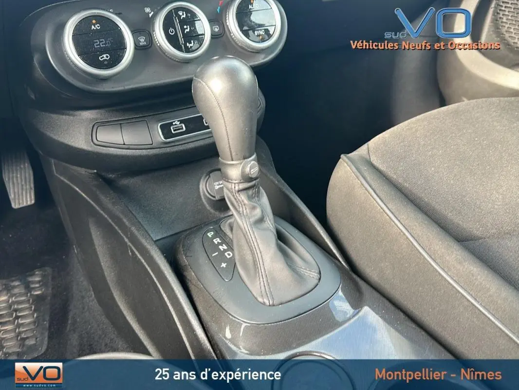 Gros plan sur la console centrale noire de la Fiat 500X MY23 avec levier de vitesse automatique et commandes de climatisation.