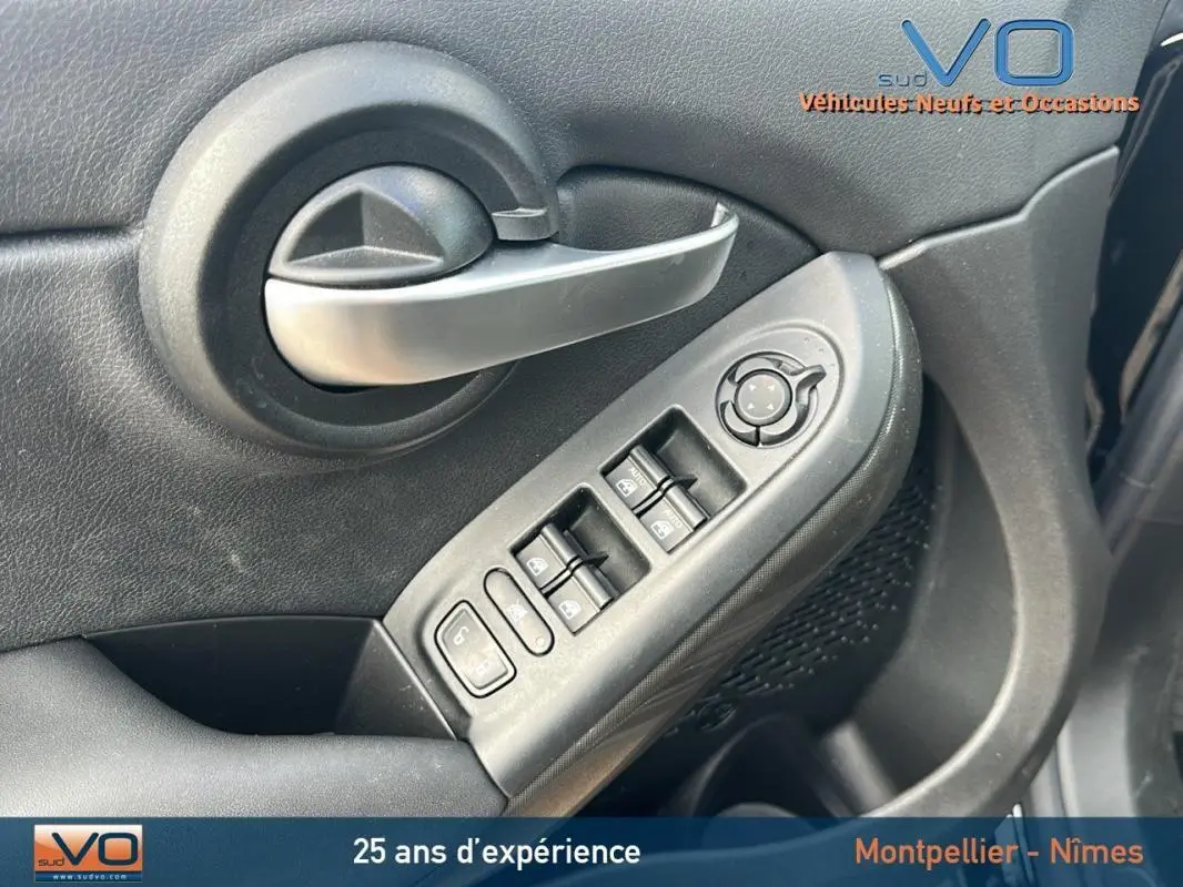 Gros plan sur la commande des vitres électriques et poignée intérieure côté gauche d’une FIAT 500X noire MY23.