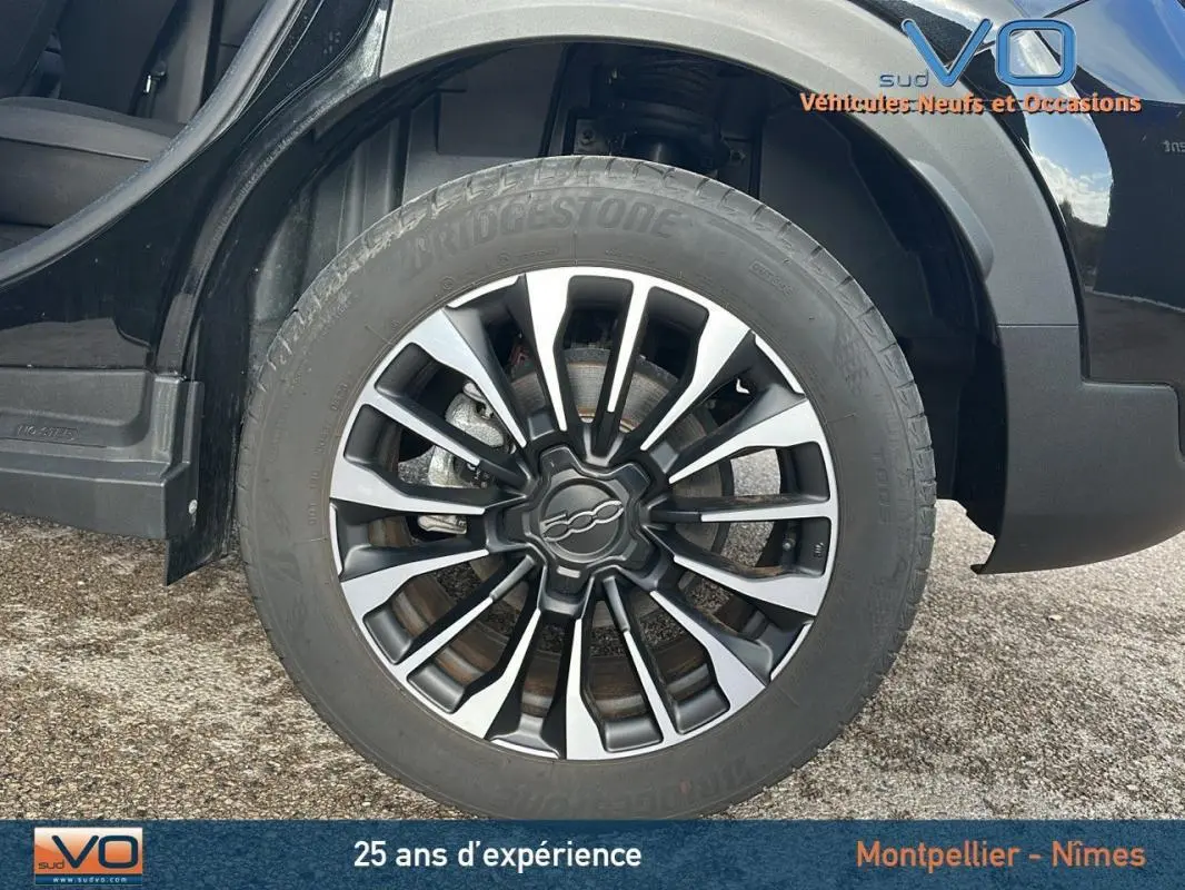 Gros plan sur la roue avant gauche noire du FIAT 500X MY23 avec jante 16 pouces au design classique bicolore.