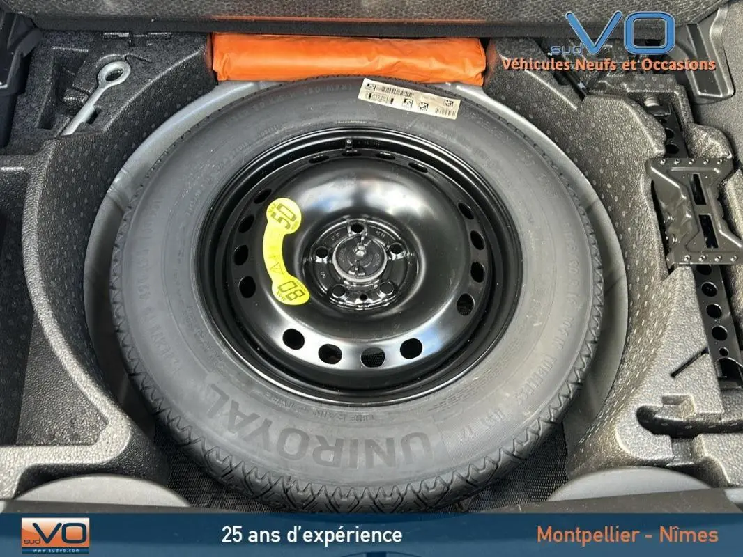 Gros plan sur la roue de secours noire et ses accessoires dans le coffre d'une FIAT 500X MY23 noire.