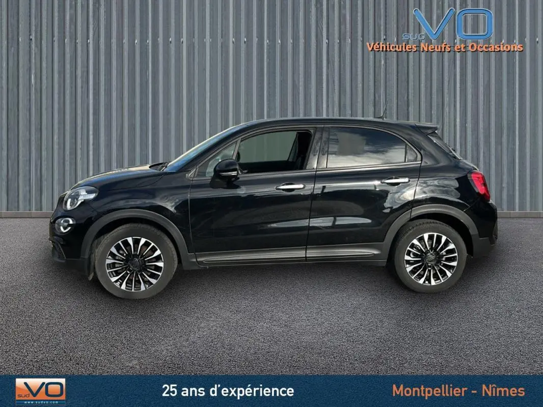 Profil côté gauche d'un FIAT 500X noir MY23 avec jantes classiques 16 pouces sur fond industriel.