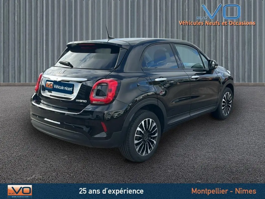 Vue 3/4 arrière droite d'un FIAT 500X noir hybride 2023 avec jantes classiques et feux arrière distinctifs.