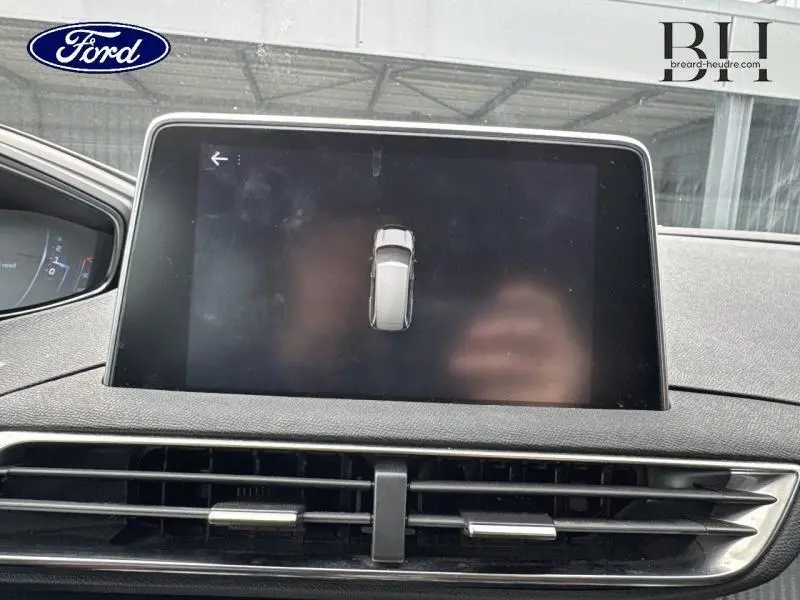 Écran tactile central affichant une vue aérienne du Peugeot 5008 gris Artense, intérieur moderne avec aérateurs noirs.