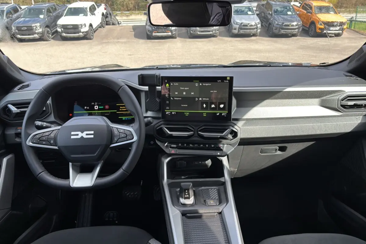 Vue intérieure du tableau de bord du Dacia Bigster Hybrid 155 Journey Plus avec écran tactile central et volant cuir noir.