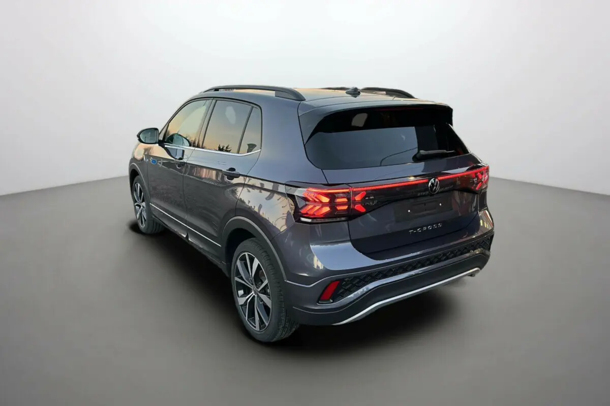 Volkswagen T-Cross TSI 116 DSG7 R-Line gris cendré vu en 3/4 arrière droit avec feux arrière LED allumés.