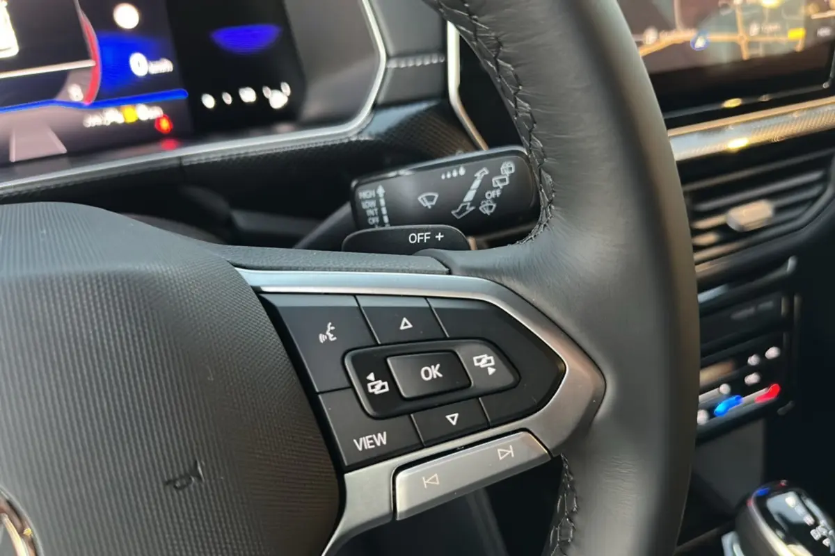 Gros plan sur les commandes multifonctions du volant cuir noir du Volkswagen T-Cross gris cendré 2025 TSI 116 DSG7 R-Line.