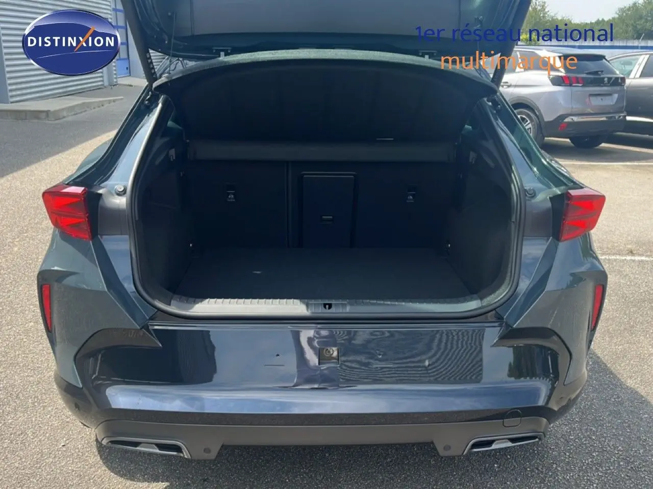 Vue arrière d’un CUPRA Formentor 1.5 eTSI 150CH DSG7 bleu Fjord Metal avec coffre ouvert montrant l’espace de chargement.