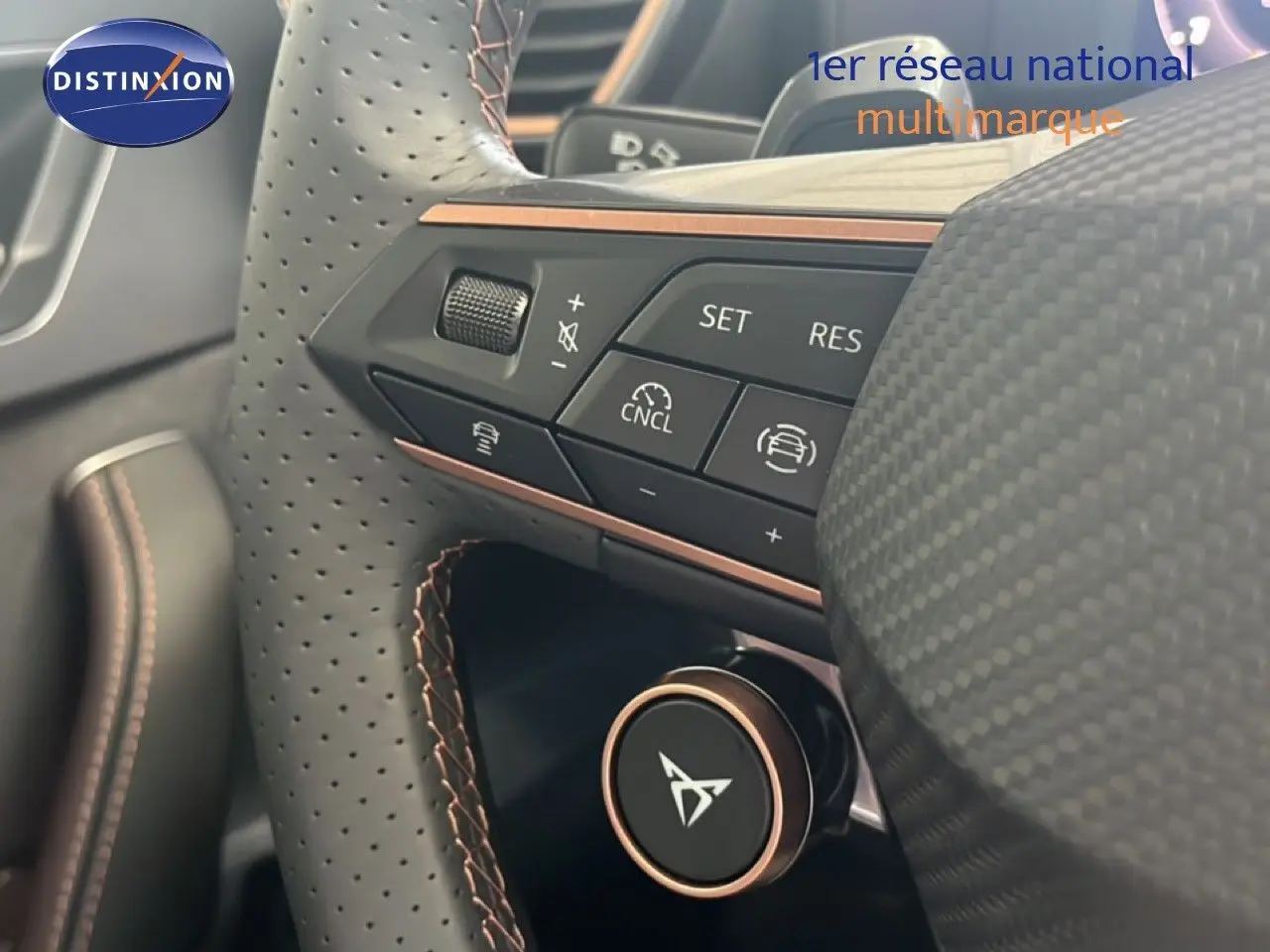 Détail du volant perforé avec commandes intégrées et logo CUPRA, finition noire et surpiqûres cuivre.
