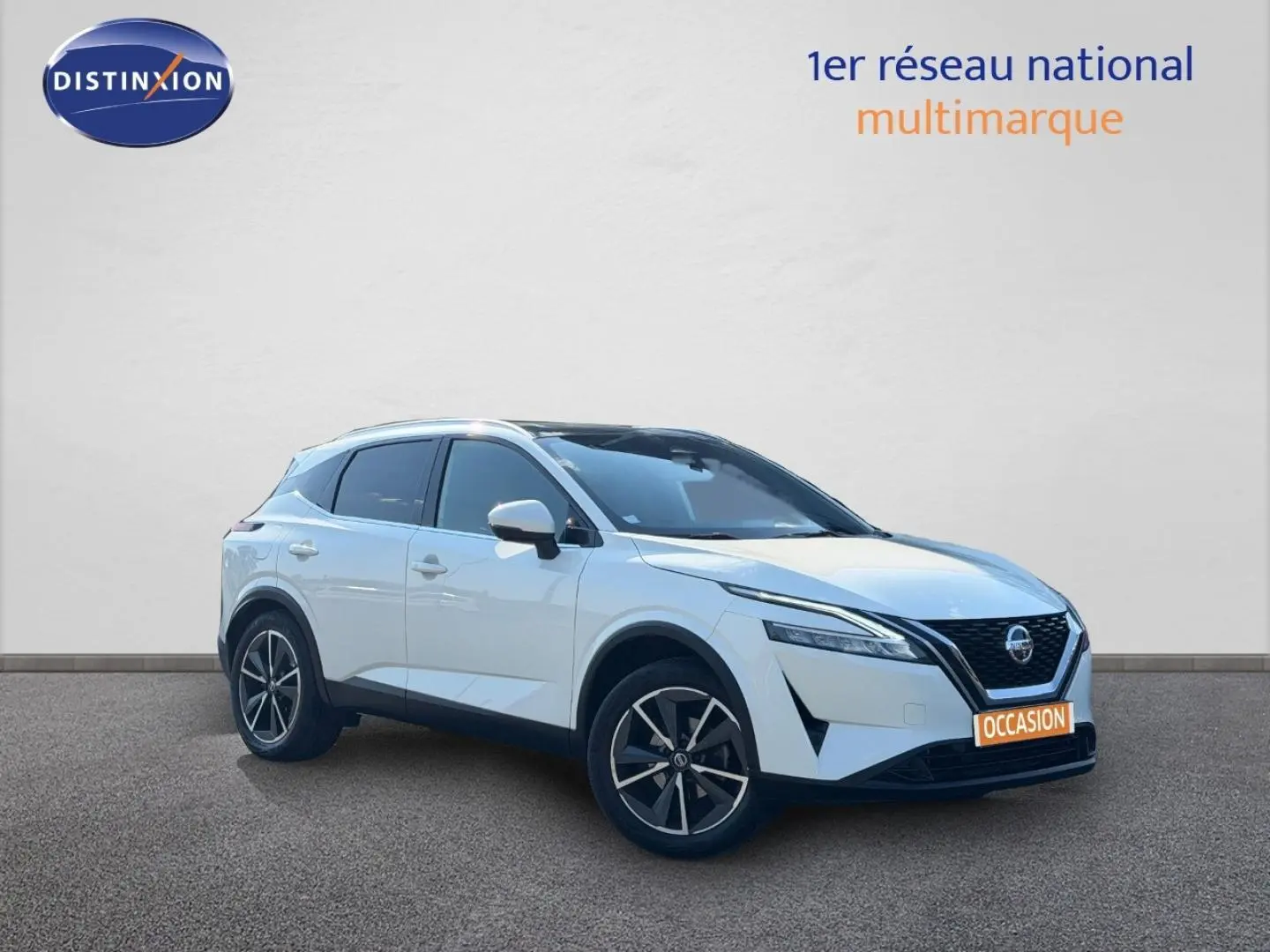 Nissan Qashqai blanc en 3/4 avant droit, avec jantes alliage noires et calandre distinctive V-Motion.
