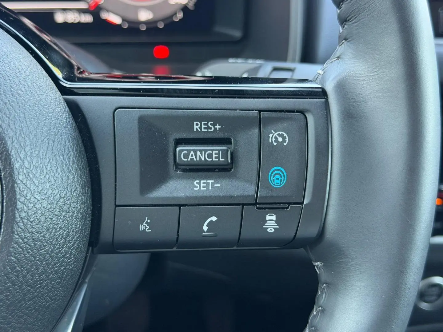 Gros plan sur les commandes de régulateur de vitesse au volant cuir noir du Nissan Qashqai Tekna 2022.