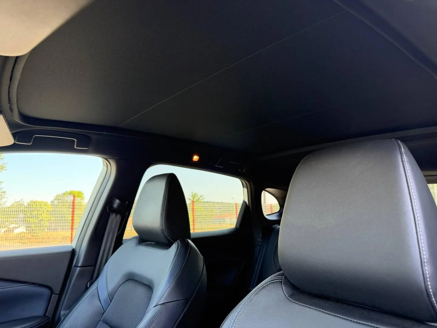 Vue intérieure du Nissan Qashqai 1.3 Mild Hybrid 2022, sièges avant en cuir noir avec surpiqûres blanches.